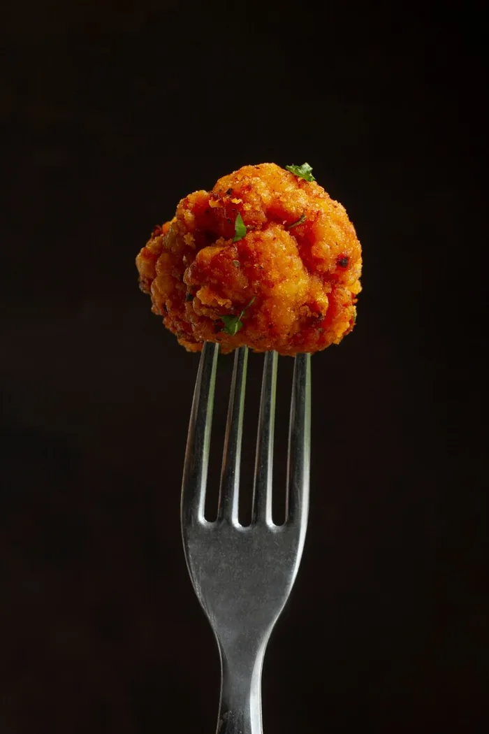 Bocado de pollo en un tenedor sobre fondo oscuro